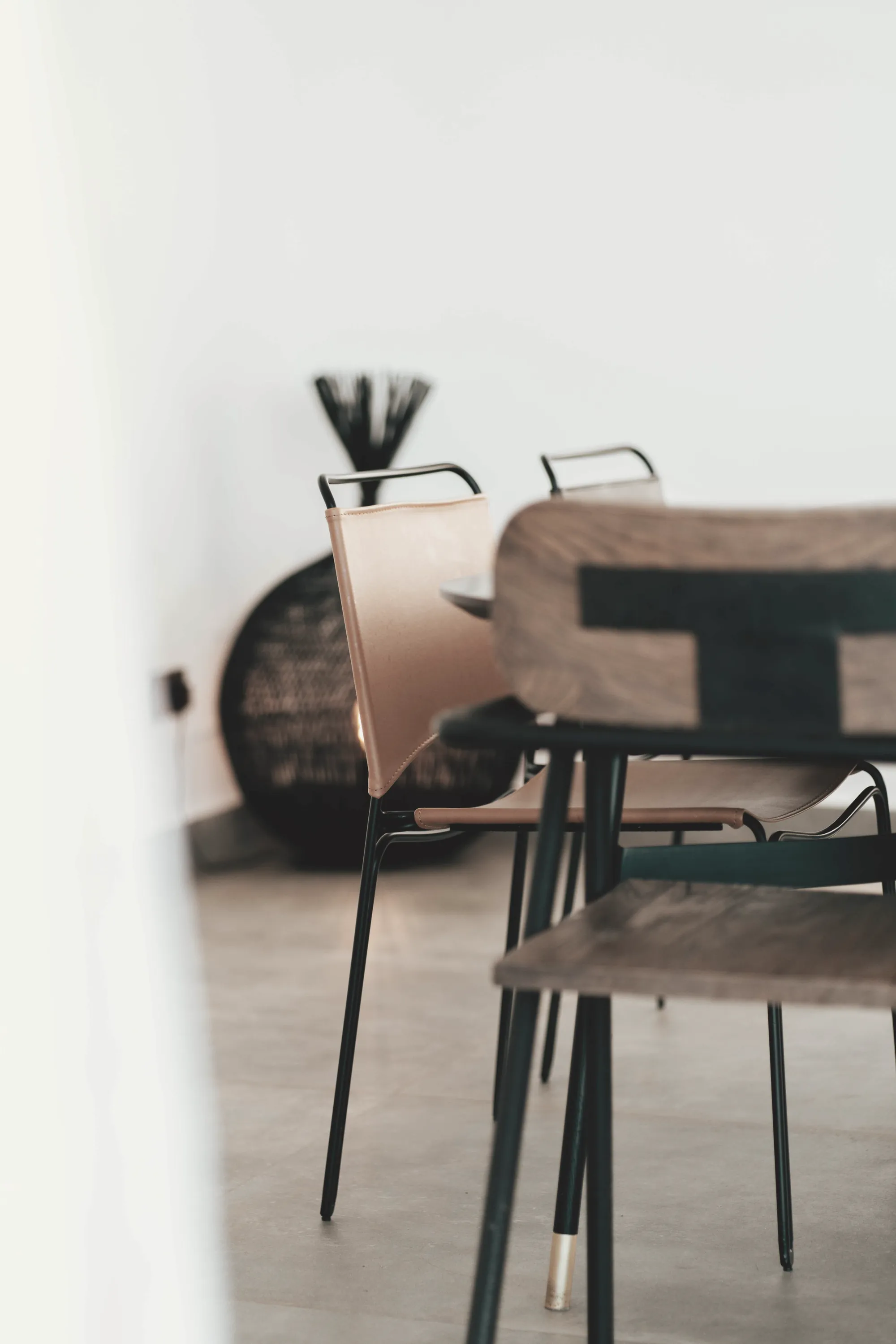 Detalle de una silla de madera y cuero junto a un muro encalado.