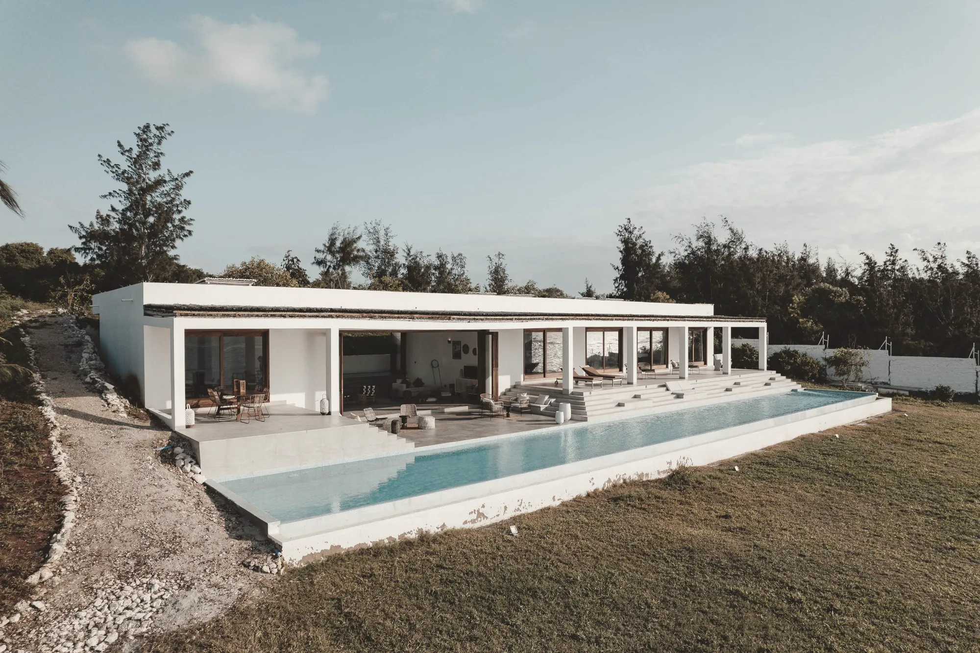 Casa blanca de una planta con una piscina desbordante sobre el cabo.
