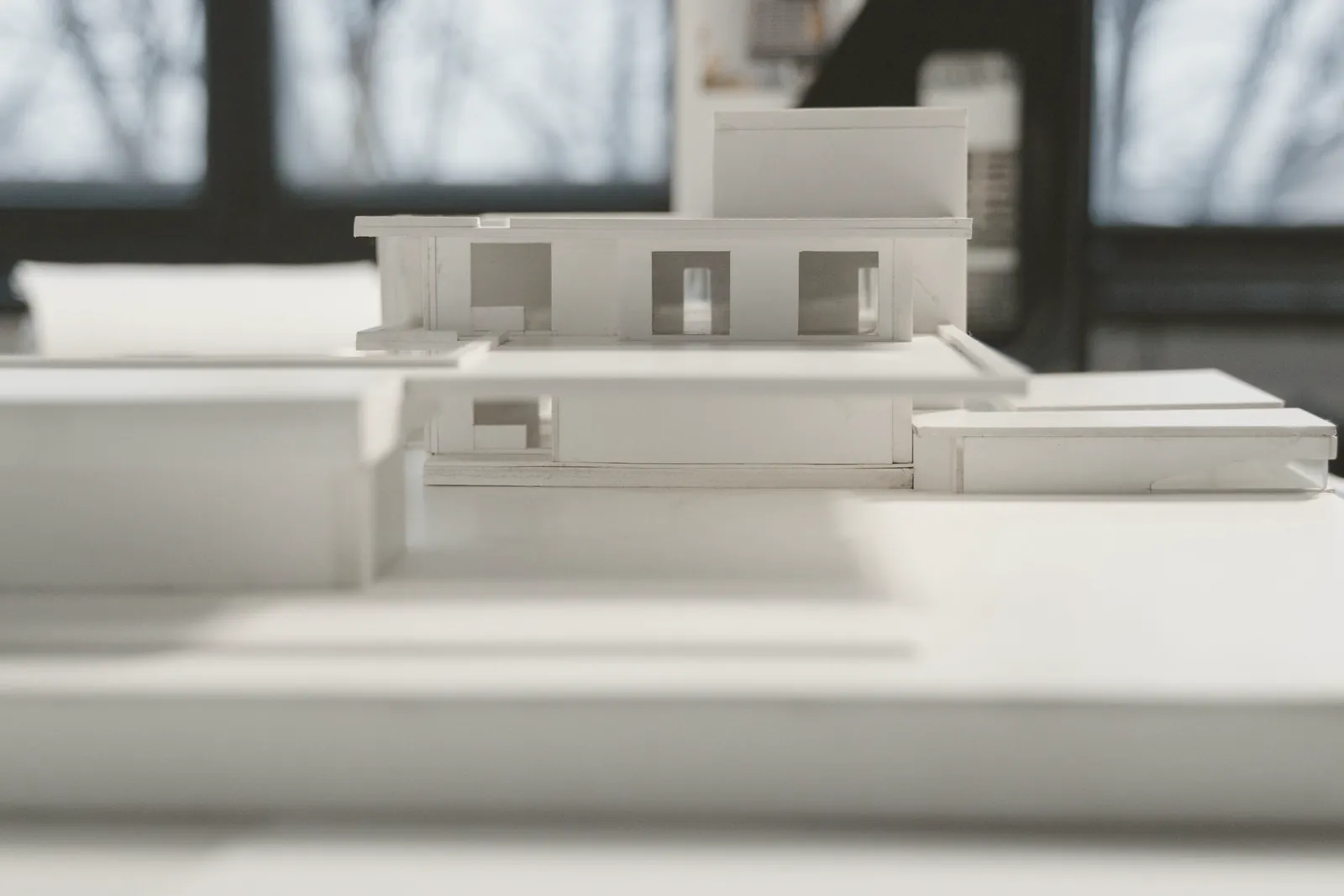 Maqueta blanca de una casa de una planta sobre la mesa del estudio.